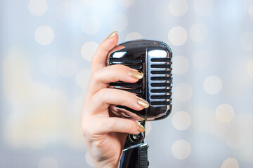 Female hand with retro microphone. Woman singing songs on the stage