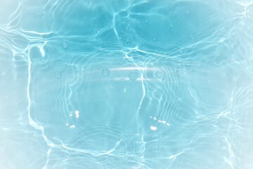Blue water with ripples on the surface. Defocus blurred transparent blue colored clear calm water surface texture with splashes and bubbles. Water waves with shining pattern texture background.