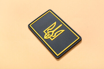 Military badge of Ukrainian army with trident on beige background