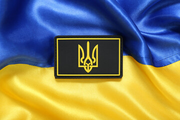 Military badge with trident on flag of Ukraine, closeup