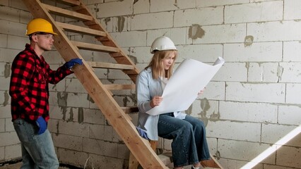 Team of professionals analyzing blueprints inside building under construction