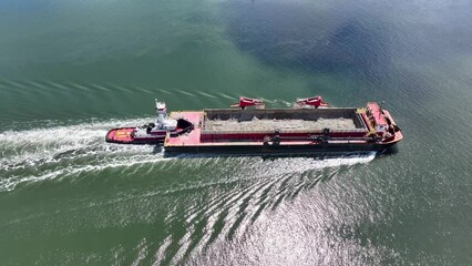 Closeup Aerial view of a dredge container being pushed by a tugboat down the Raritan River in Perth Amboy, New Jersey