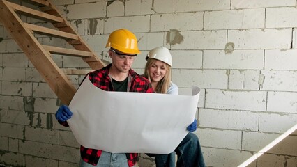Cheerful female architect discussing blueprint with builder inside new building