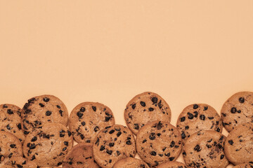 Sweet cookies with chocolate chips on brown background