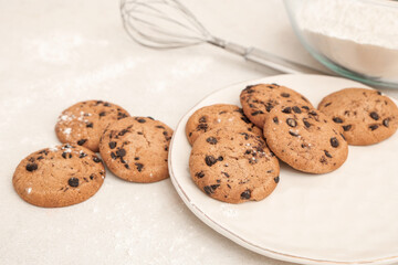 Plate of sweet cookies with chocolate chips on white background