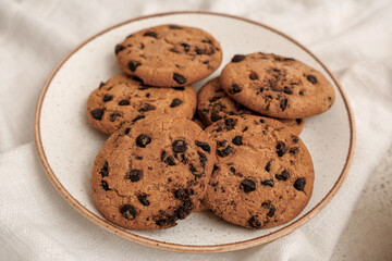 Plate of sweet cookies with chocolate chips on white background, closeup
