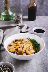 Funchose rice noodles with mushrooms and green onions in a bowl on the table vertical view