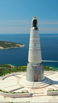 Aerial view of the Our Lady Of Loreto Statue with a view on Primosten town, Croatia. Drone orbit shot. Popular tourist destination on the Adriatic Sea coast in Croatia.