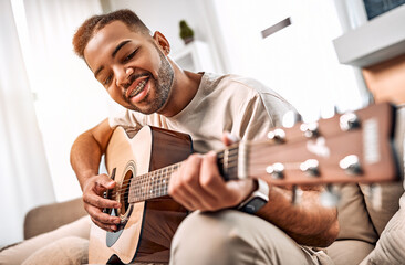 Favorite hobby. Handsome african american man playing guitar at home in living room.