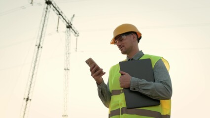 Smiling power line inspector using cellphone after transmission tower audit