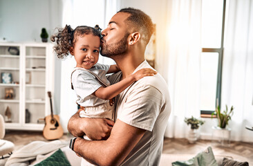 Caring dad holds his little daughter in his arms and kisses her. Love and care. Father's day.