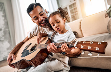  Dad teaches daughter to play guitar in living room. A little african american girl is singing. Dad and daughter spend time together.