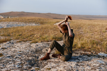 Woman enjoying serene nature beauty while sitting on a rock in the middle of a field
