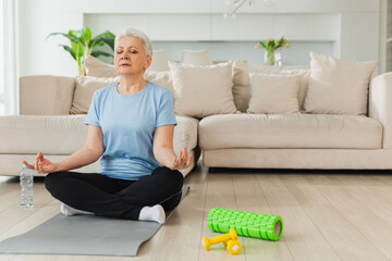 Yoga mindfulness meditation. Senior adult mature woman practicing yoga at home. Mid age old lady...
