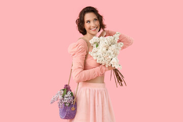 Happy young woman with bouquet of blooming white lilac flowers on pink background