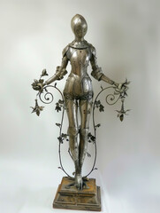 Ornate Female Knight Armor Statue with Floral Decorations in a minimalist room with white walls, medieval figure