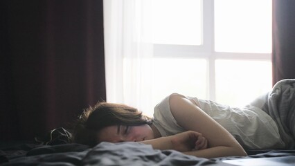 Young woman sleeping on the bed after working on the laptop at home