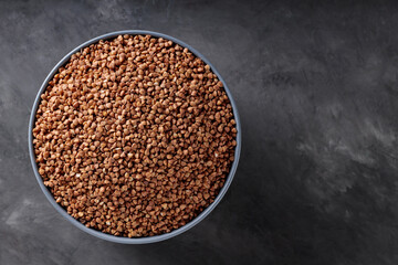 Buckwheat Grains in Gray Bowl on Dark Concrete Background, Diet Food Concept, Top View, Copy Space