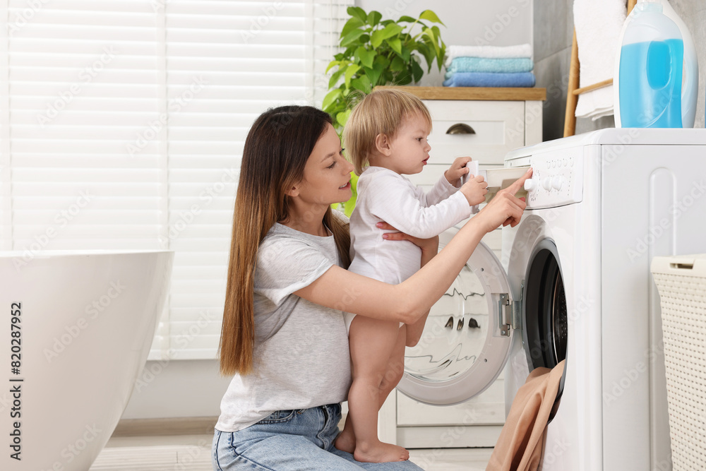 Wall mural Mother with her daughter washing baby clothes in bathroom