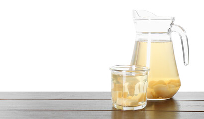 Delicious quince drink in jug and glass on wooden table against white background