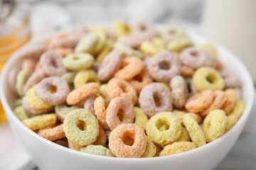 Tasty cereal rings in bowl on table, closeup