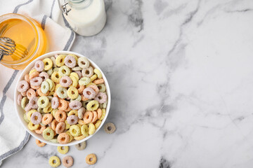 Tasty cereal rings in bowl, milk and honey on white marble table, flat lay. Space for text