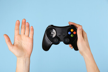 Woman with game controller on light blue background, closeup