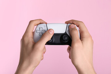 Man using wireless game controller on pink background, closeup