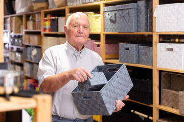 Adult man pensioner choosing storage basket at store of household goods