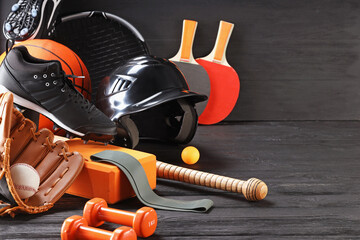 Many different sports equipment on dark grey wooden table, space for text