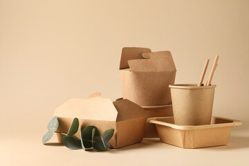 Eco friendly food packaging. Paper containers, tableware and eucalyptus branch on beige background