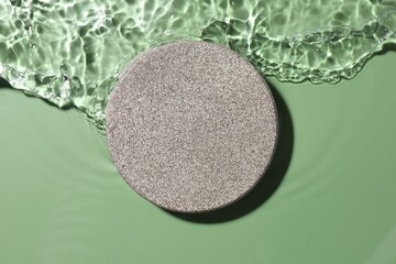 Presentation for product. Stone podium in water on green background, top view