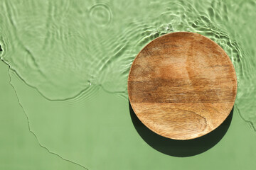 Presentation of product. Wooden podium in water on green background, top view. Space for text