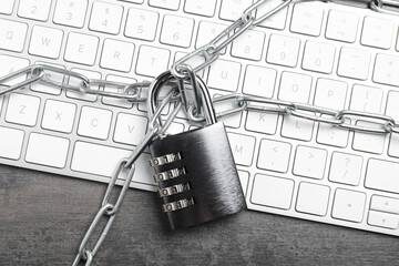 Cyber security. Metal combination padlock with chain and keyboard on grey table, top view