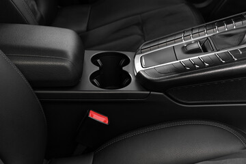 Cup holders and seat inside of modern black car, closeup