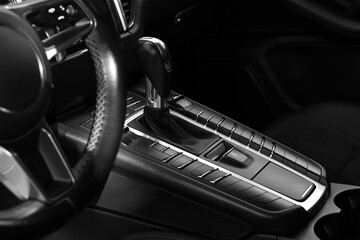 Gear stick and steering wheel inside of modern black car