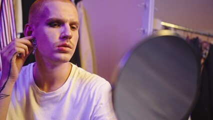 Fototapeta premium Close-Up: LGBT Individual Trying on Earrings by Large Mirror