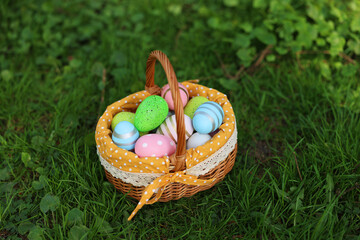 Easter celebration. Painted eggs in wicker basket on green grass
