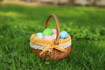 Easter celebration. Painted eggs in wicker basket on green grass