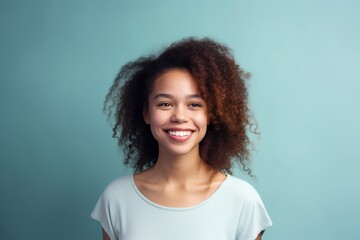 A woman with curly hair is smiling and wearing a white shirt