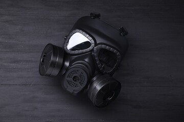 One gas mask on black wooden background, top view