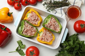 Raw stuffed peppers and ingredients on white table, flat lay