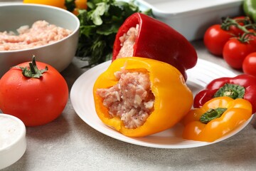 Raw stuffed peppers, ground meat and ingredients on grey table, closeup