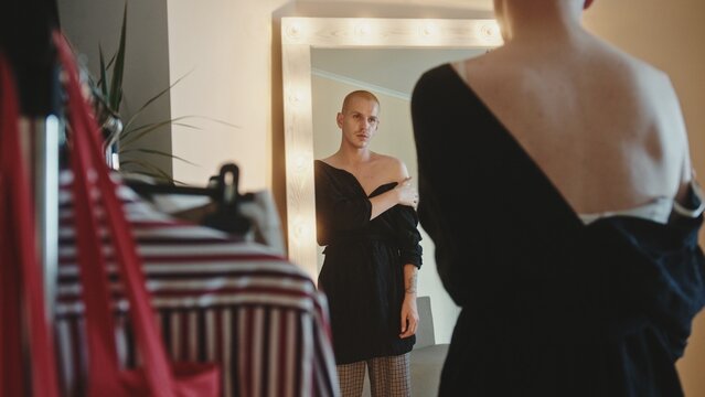 Extravagant crossdresser adjusting dress in dressing room