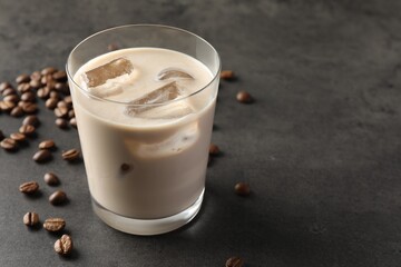 Coffee cream liqueur in glass and beans on grey table, space for text