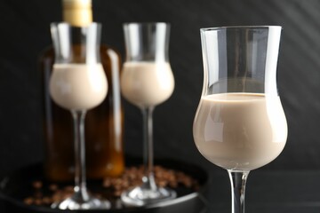 Coffee cream liqueur in glasses, bottle and beans on table, closeup
