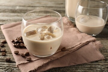 Coffee cream liqueur in glasses and beans on wooden table, closeup