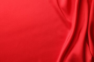 Crumpled red silk fabric as background, top view. Space for text