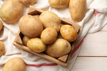Raw fresh potatoes with crate on light wooden table, top view