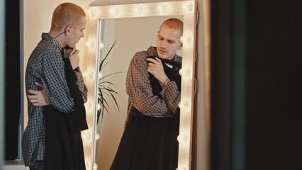 Young Man at Illuminated Mirror Trying on a Dress, Exploring Gender Identity